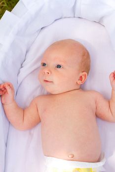 A newborn baby is looking around with his eyes open.