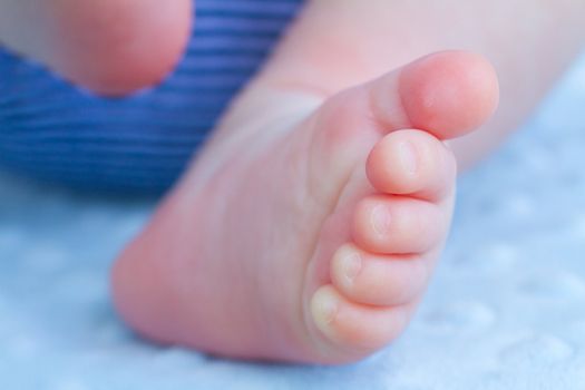 The feet of a newborn baby photographed from below outdoors.