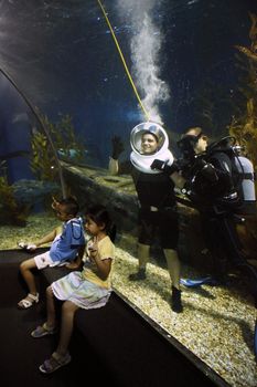 Brave tourist diving in a huge ocean aquarium with sharks and People watching him in Siam Ocean World, Bangkok, Thailand - 16.08.2011