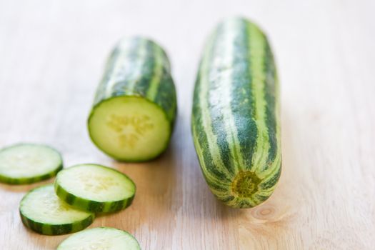 Fresh uncooked green stripe cucumber on chopping board