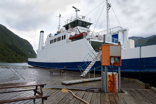 Ferry at wooden pier with electric cable connected to outlet