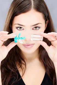 Young woman holding contact lenses wash container in front of her face