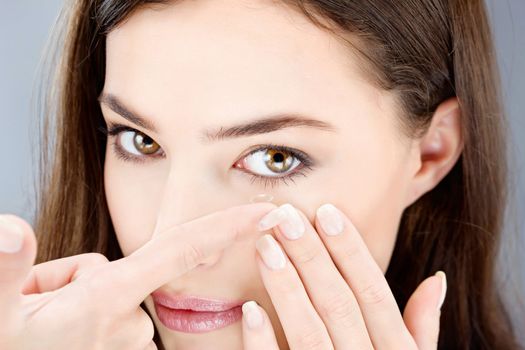 Close up of a woman putting contact lens in her eye