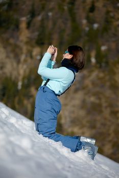 Female skier taking photos in the snow