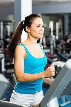 attractive young woman runs on a treadmill, is engaged in fitness sport club