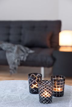 Tea-lights in glass candle holders decorating living room with gray sofa.