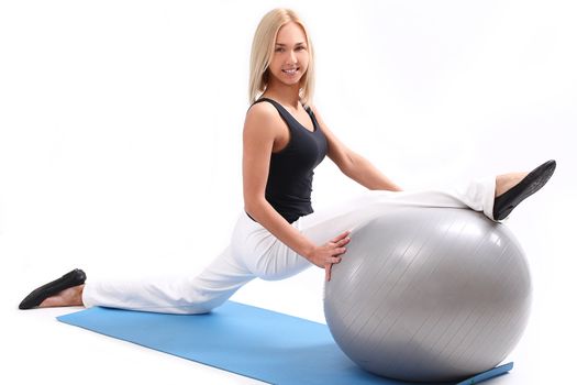 Young and beautiful woman doing exercise with fitness ball lying on a blue mat