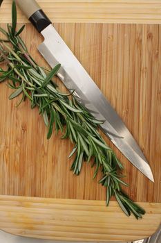 A bouquet of rosemary herbs on a weathered old chopping board.