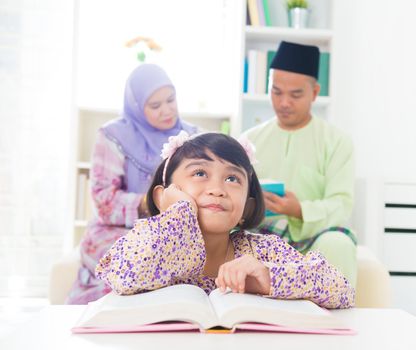 Southeast Asian family reading book at home. Muslim family living lifestyle.