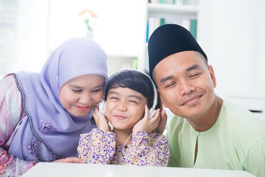 Southeast Asian family listen mp3, sharing headphone. Muslim family living lifestyle