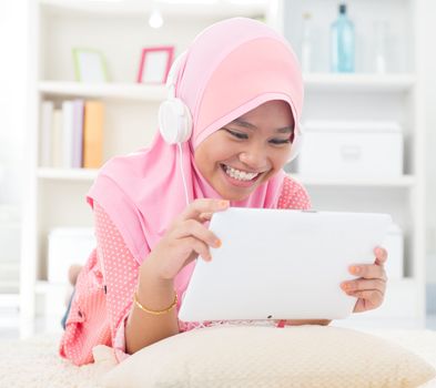 Southeast Asian teenager listen mp3 headphone at home. Muslim teen girl living lifestyle.