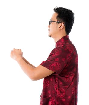 Side view Southeast Asian Chinese man in traditional Chinese Tang suit greeting, isolated on white background