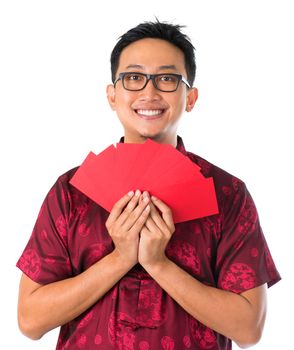 Happy Southeast Asian Chinese male in cheongsam hands holding many red packets / ang pow, isolated on white background.