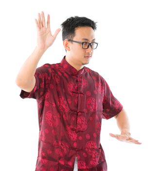 Southeast Asian Chinese male practicing tai chi, isolated on white background