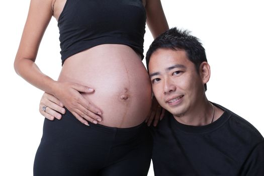 Young asian man hugging his wife, 37 weeks pregnant, both dressed in black