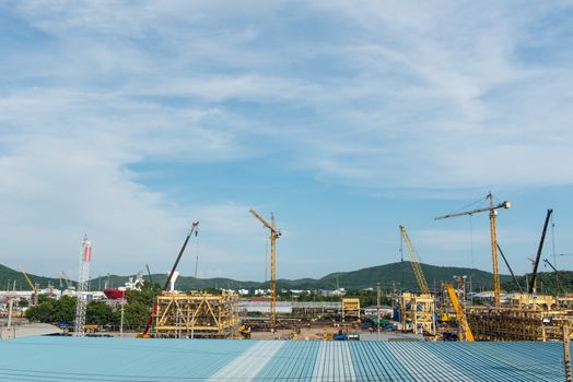 Large construction site with multiple metal cranes, taken on a sunny day