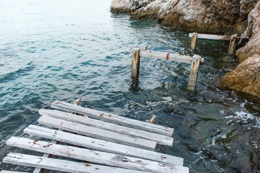 Old vintage wooden walking bridge over sea water, taken on a sunny day