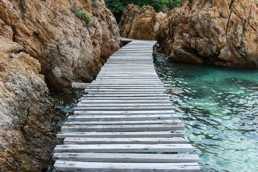 Old vintage wooden walking bridge over sea water, taken on a sunny day