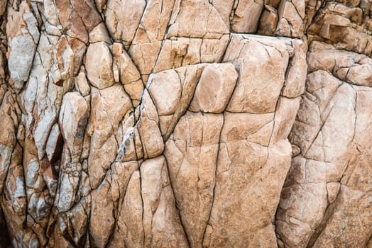 Solid limestone rock texture with muliple cracks, taken near the beach on a sunny day