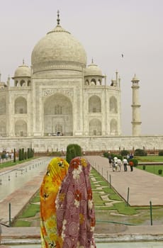 Indian Ladies in colorful saris at the Taj Mahal. White marble mausoleum in Agra, India.