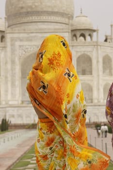 Indian Lady in colorful sariy at the Taj Mahal. White marble mausoleum in Agra, India.