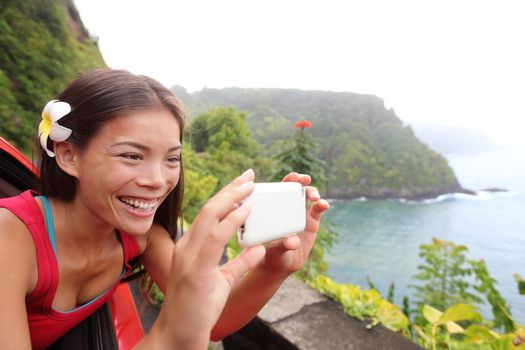 Tourist on Hawaii taking photo with camera phone during car road trip on the famous Road to