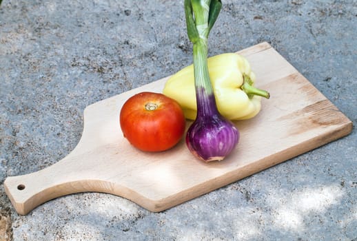 tomato, onion, pepper on wooden cutting board 