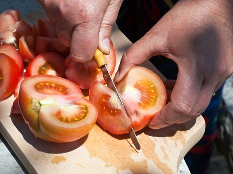 slicing tomato on wooden cutting board