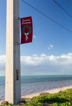 Seasons Greetings on sign by beach by roadside in Florida Keys by Route 1 Overseas Highway