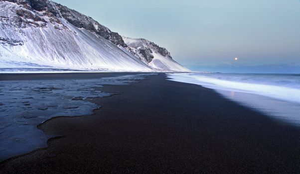 Iceland coastline in winter a line of ice freezes instantly as the tide hits the black volcanic sand