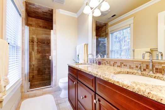 Large bathroom interior  with cherry cabinets and granite countertop.