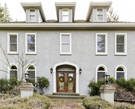 Home exterior of large grey classic house with many narrow windows.