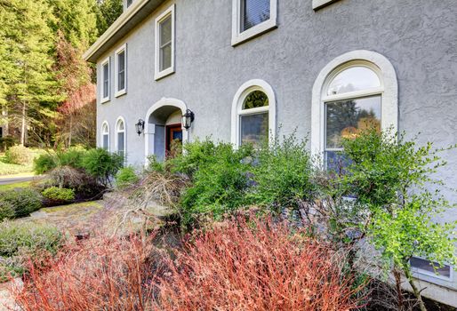 Home exterior of large grey classic house with many narrow windows.