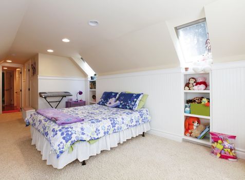 Girl bedroom with attic  vaulted ceiling and beige carpet with toys.