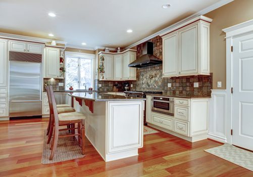 Large white luxury kitchen with cherry hardwood and stone tiles.