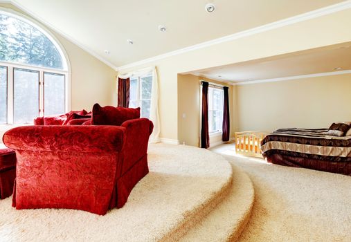 Large bright bedroom with red sofa and beige tones.