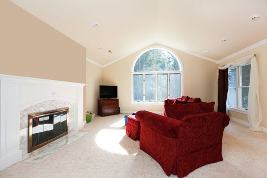 Large bright living room with red sofa and white fireplace.