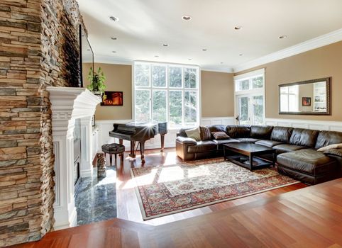 Bright luxury living room with stone fireplace and cherry hardwood with leather sofas.