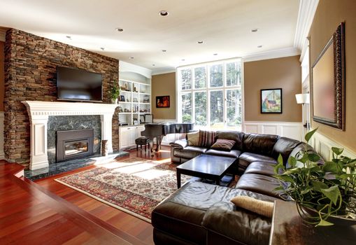 Luxury living room with stobe fireplace and leather sofas, cherry hardwood and nice rug.