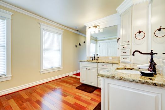 Luxury large white master bathroom with cherry hardwood and double  corner sinks.