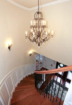 Luxury curved staircase with chandelier, cherry harwood and white trim.