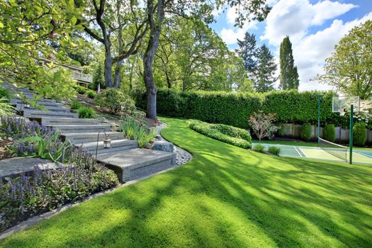 Tennis court with house landscape on the hill  and bright green grass.