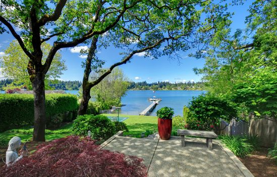 Tennis court with lake and bright green grass.