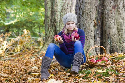 young girl with basket of apples in autumn garden