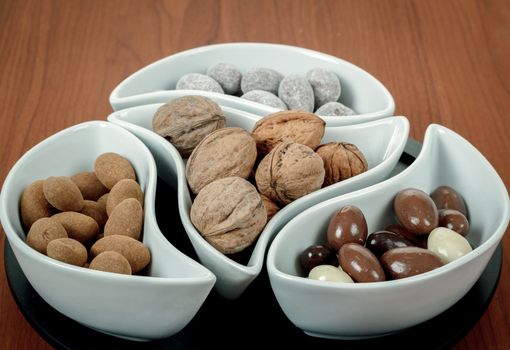 almonds in chocolate and walnuts on woden background