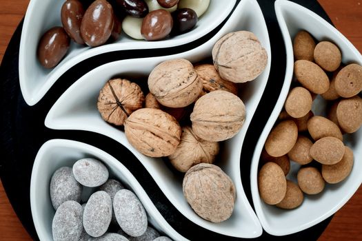 detail of almonds in chocolate and walnuts on woden background