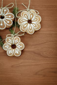 Gingerbread cookies with twig hanging over wooden background