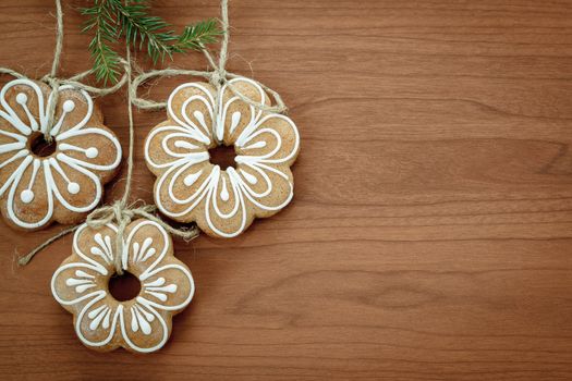 Gingerbread cookies with twig hanging over wooden background