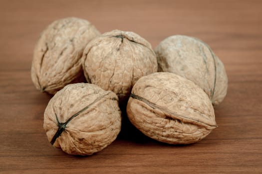 close up of five walnuts on brown wooden background