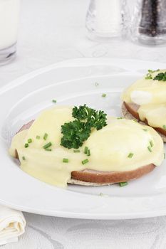 Breakfast of Egg Benedict and ham with Hollandaise sauce over sandwich thins.